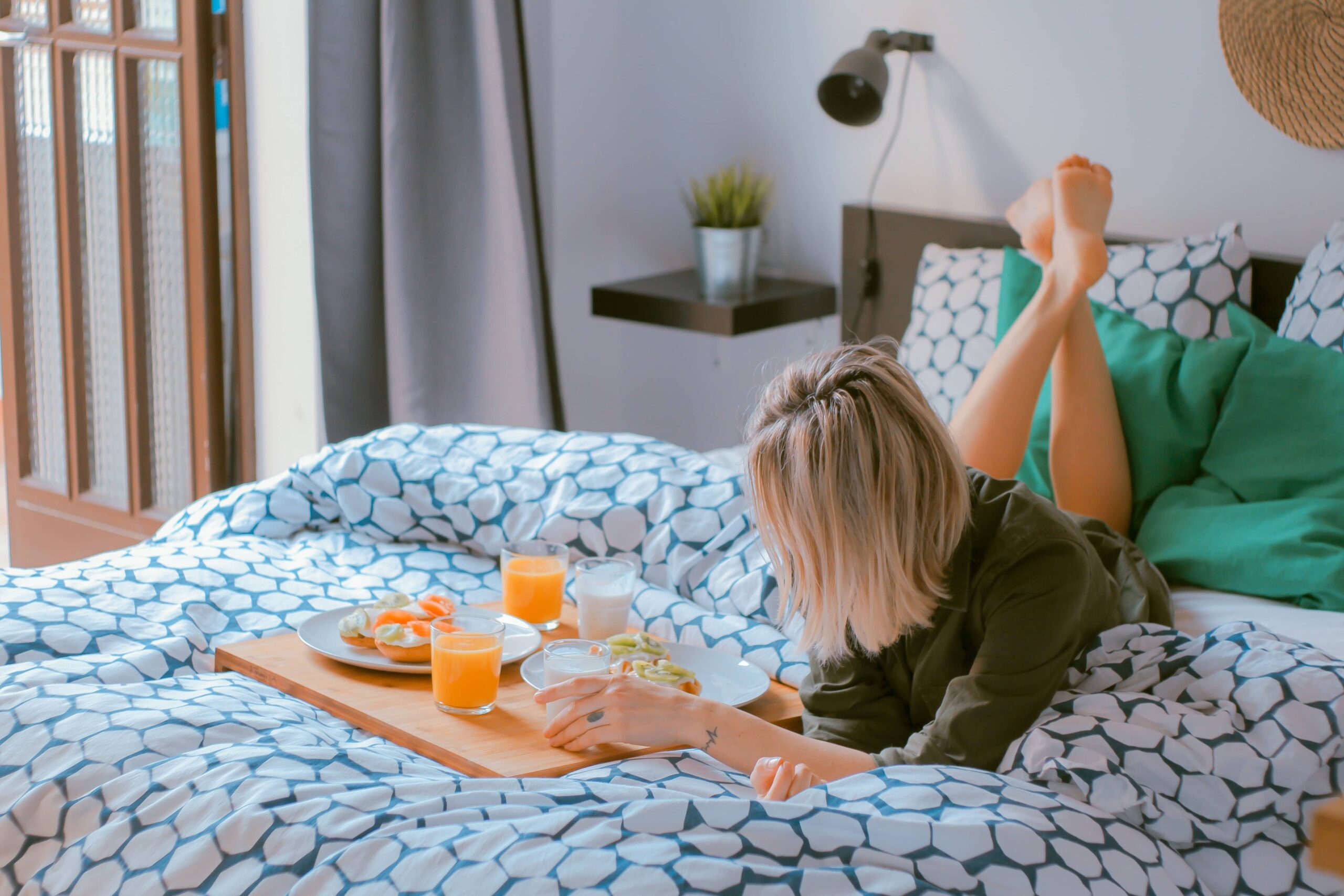 Woman lying on the bed with a breakfast board | bed and breakfast software