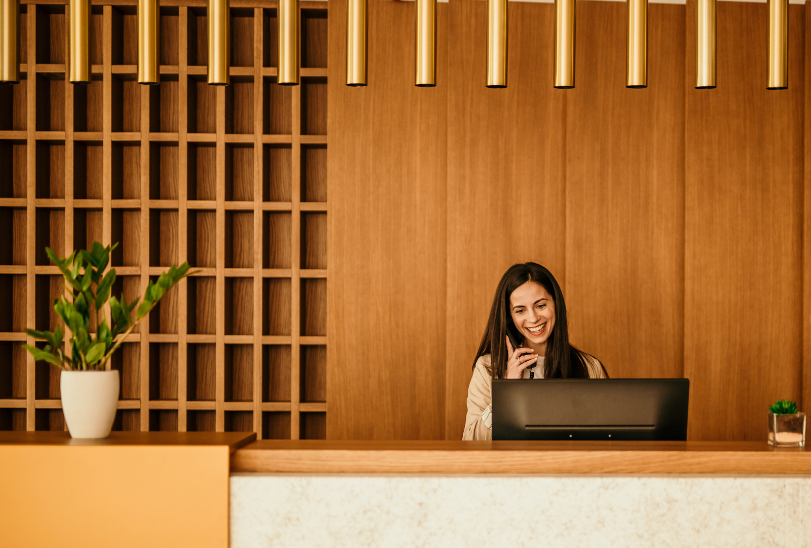 Female Hotel Staff smiling on he phone at computer.