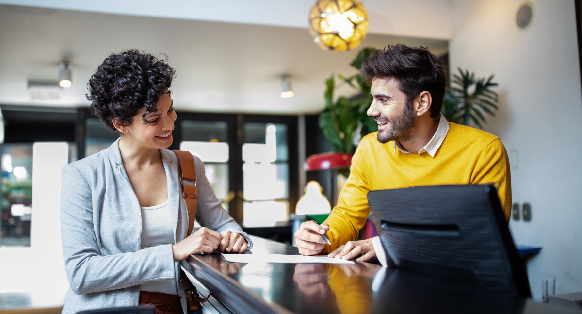 Male front desk hotel staff smiling at guest